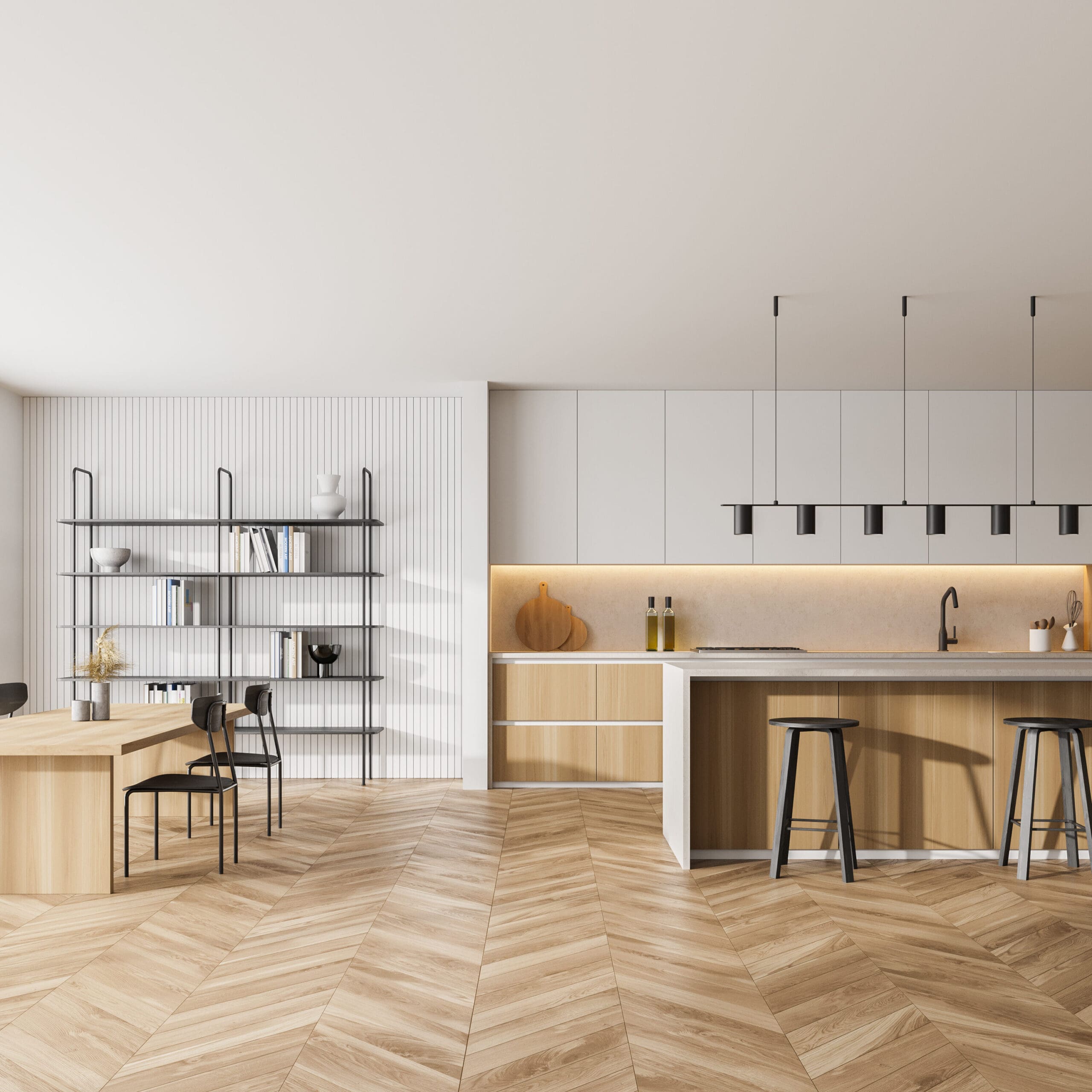 A modern kitchen with a minimalist design features a wooden island with black stools, a sleek white countertop, and built-in cabinets. A dining area with a wooden table and black chairs is adjacent, alongside shelving with decorative items.