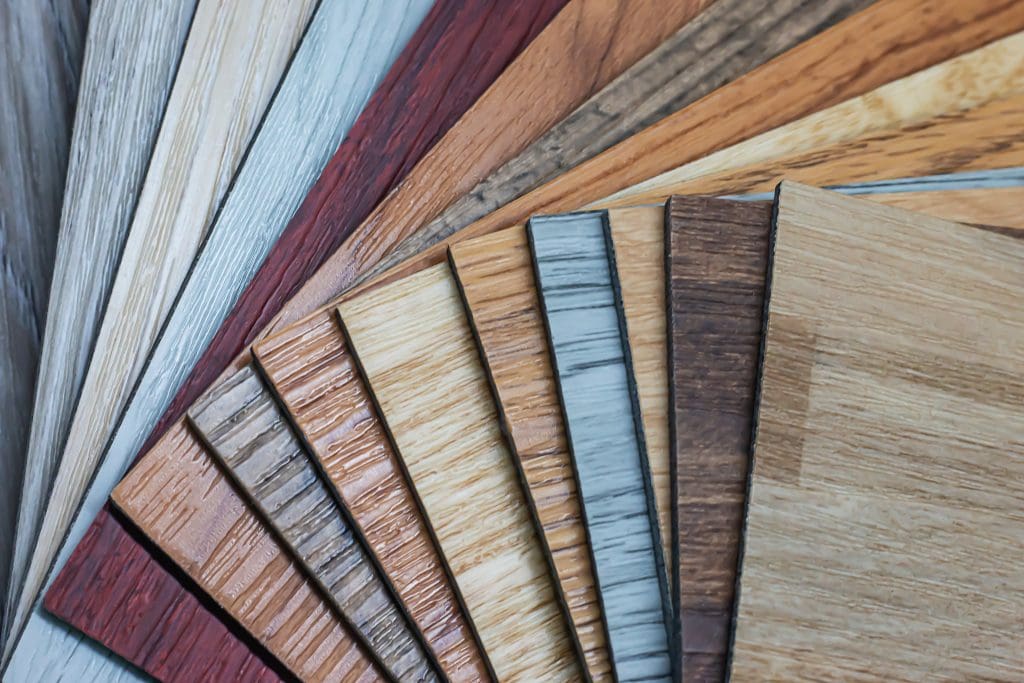 A fan-shaped arrangement of various wooden laminate samples in different colors and textures, ranging from light to dark shades. The samples display intricate wood grain patterns, showcasing a variety of natural finishes.